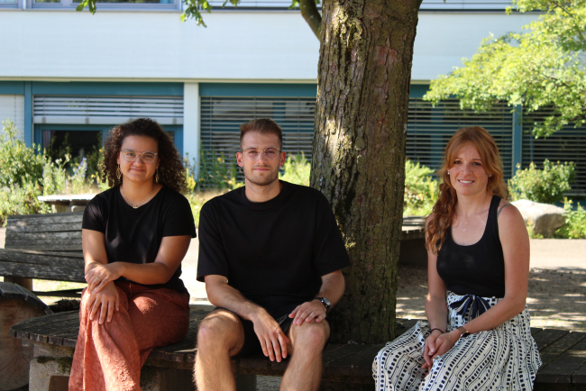 Sarah Kälin da Silva, Daniel Kálóczi und Tabea Lanz sitzen vor dem Schulhaus in Burgdorf