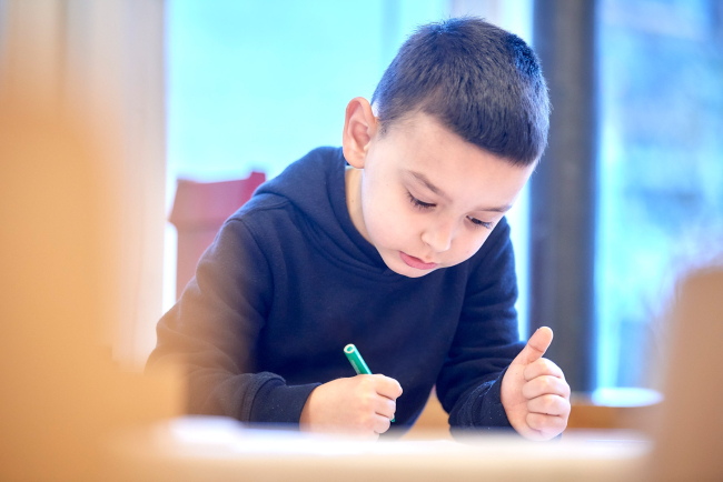 Kind mit grünem Stift in der Hand, das etwas zeichnet