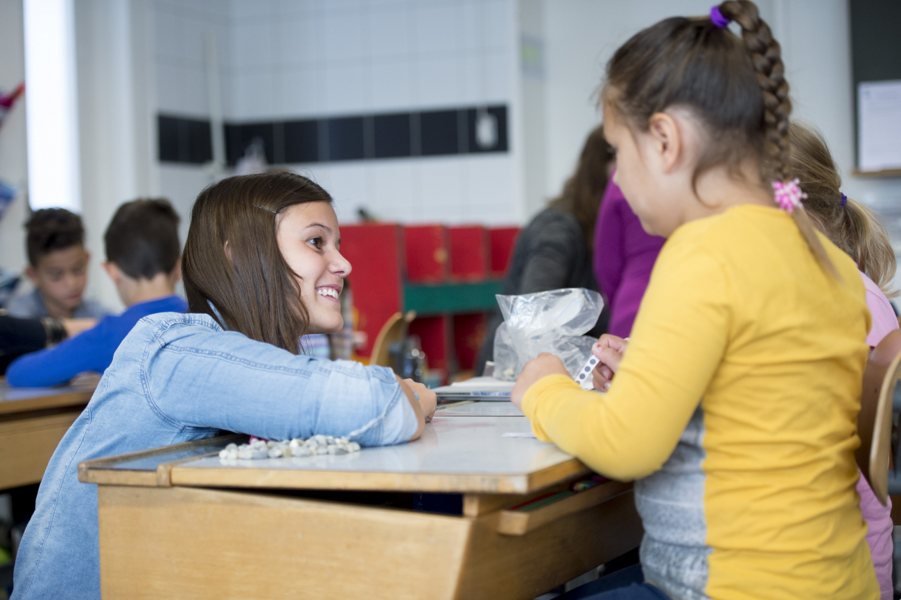 Eine Lehrerin erklärt einer Schülerin etwas am Pult.