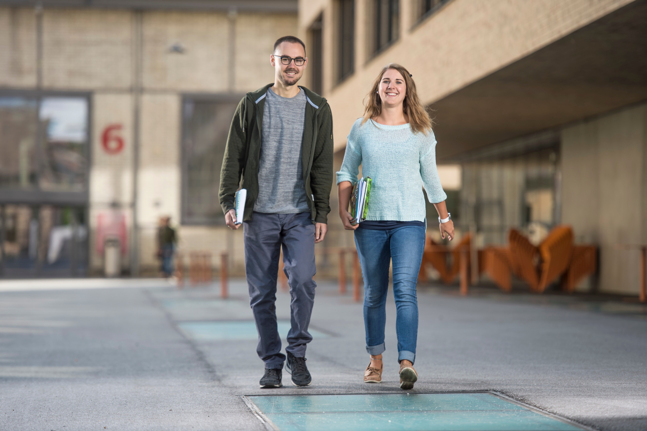 Ein Student und eine Studentin der PHBern laufen nebeneinander auf dem vonRoll-Hochschulareal.