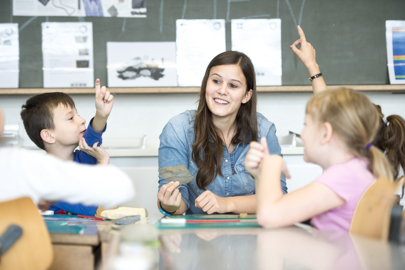 Eine junge Lehrerin unterrichtet zwei aufgeweckte Kinder.