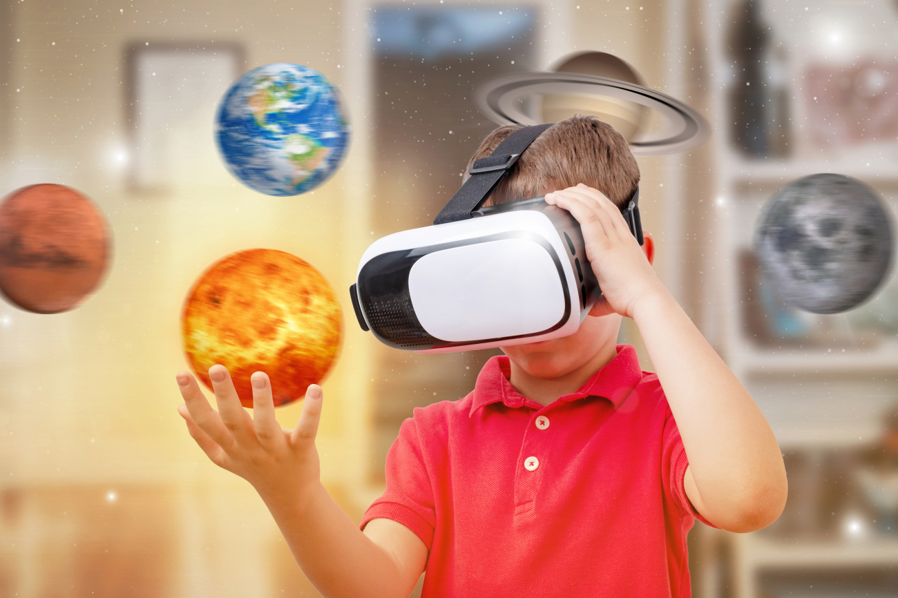 Knabe mit aufgesetzter VR-Brille greift nach Planeten im Raum