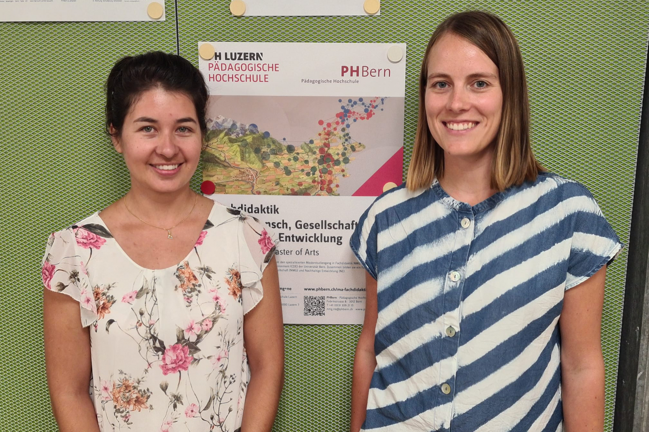 Zwei von drei Absolventinnen, stehend vor Wand