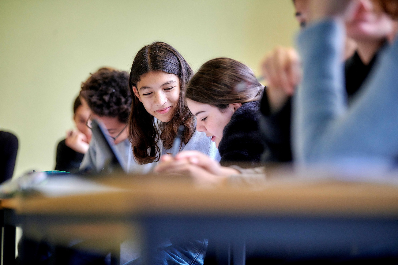 Schülerinnen und Schüler der Sekundarstufe sitzen am Pult und lösen zu zweit Aufgaben