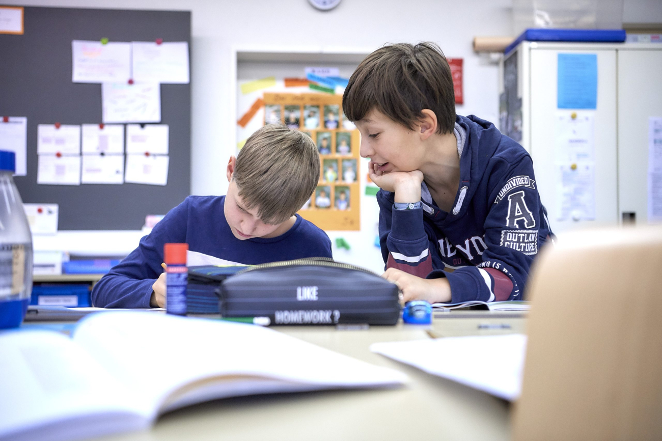 Zwei Schüler besprechen an einem Pult gemeinsam etwas