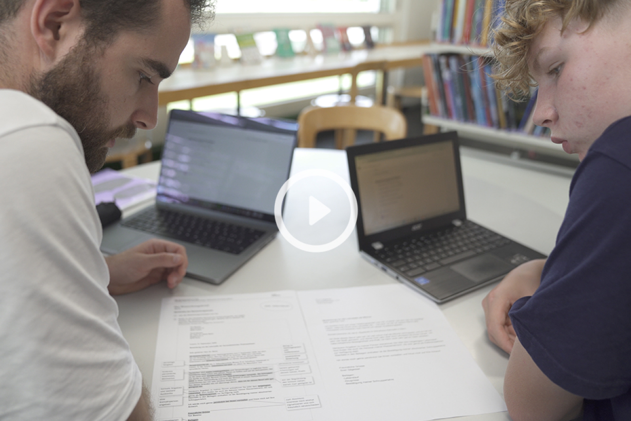 Lehrperson und Schüler studieren Bewerbungsschreiben