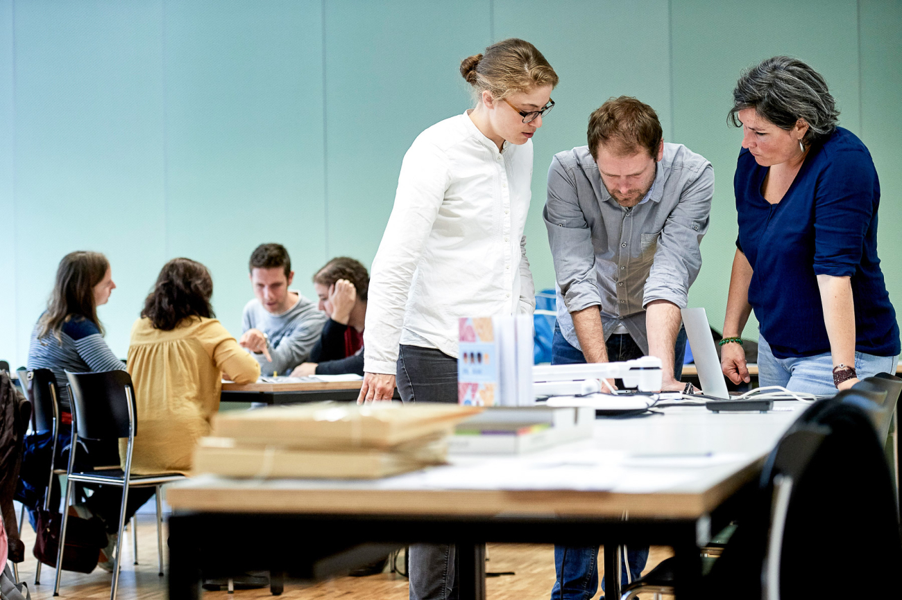 Mitarbeitende des ZBE diskutieren miteinander an einem Tisch
