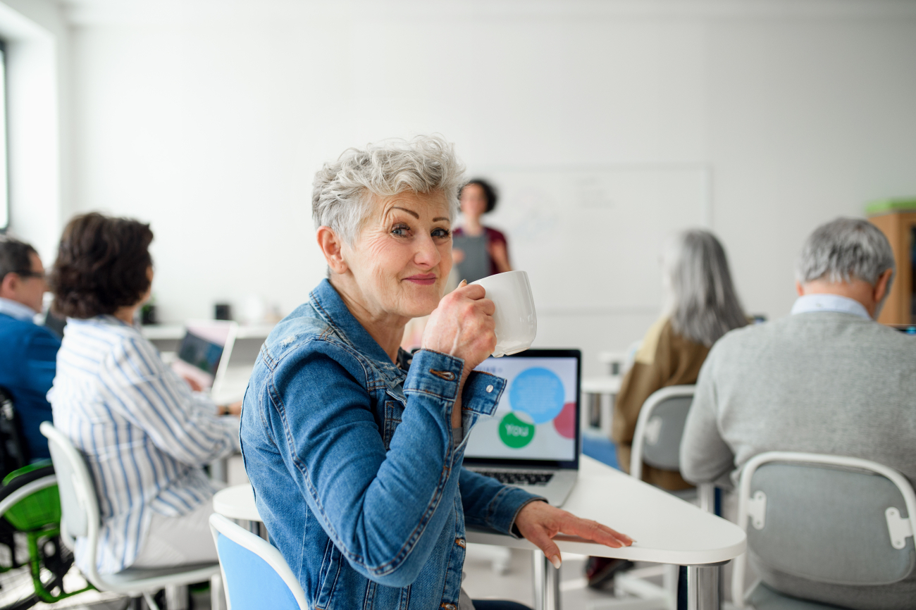 Ältere Frau in Kurssetting, mit Kaffeetasse in der Hand