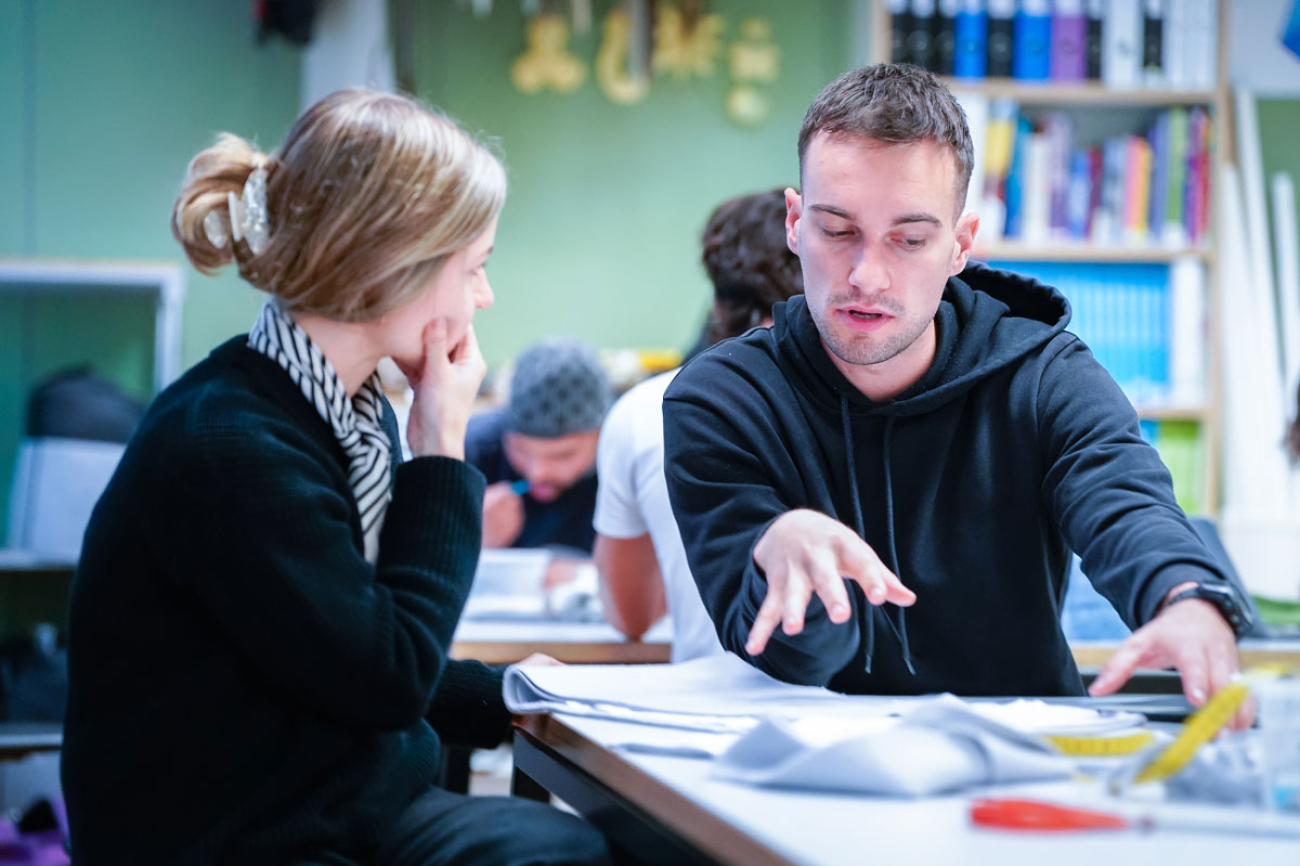 zwei Menschen diskutieren an einem Tisch mit Material drauf