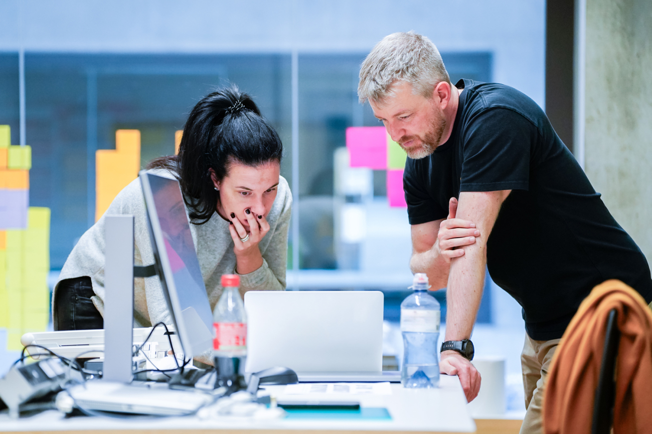 Eine Frau und ein Mann schauen zusammen in einen Laptop