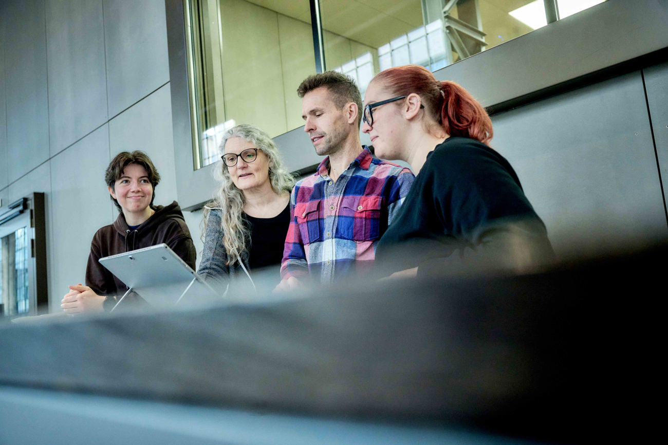 Menschen sitzen nebeneinander in einer Reihe und schauen auf einen Laptop
