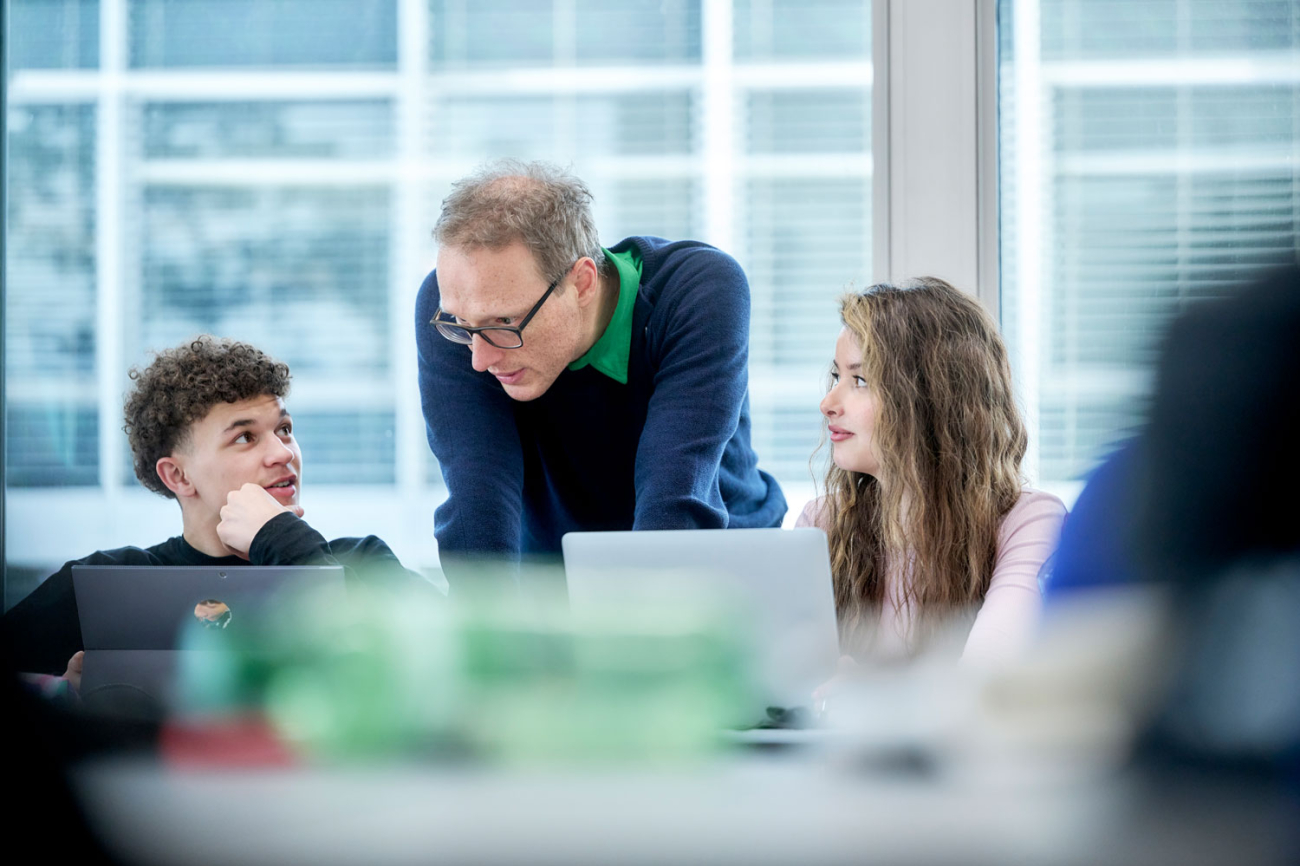 Drei Menschen schauen in einen Computer