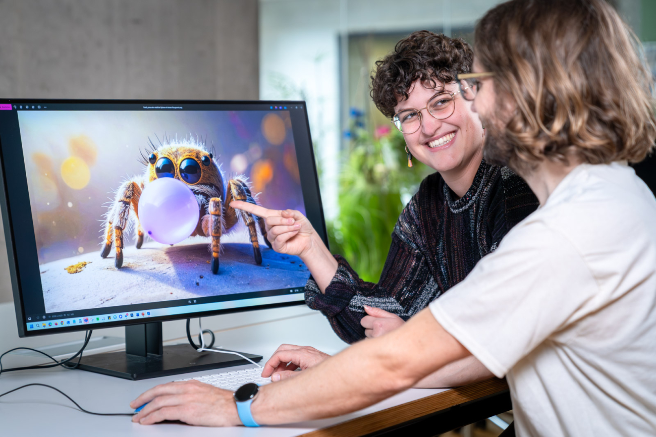 Frau und Mann vor Bildschirm, auf dem ein KI-Programm geöffnet ist