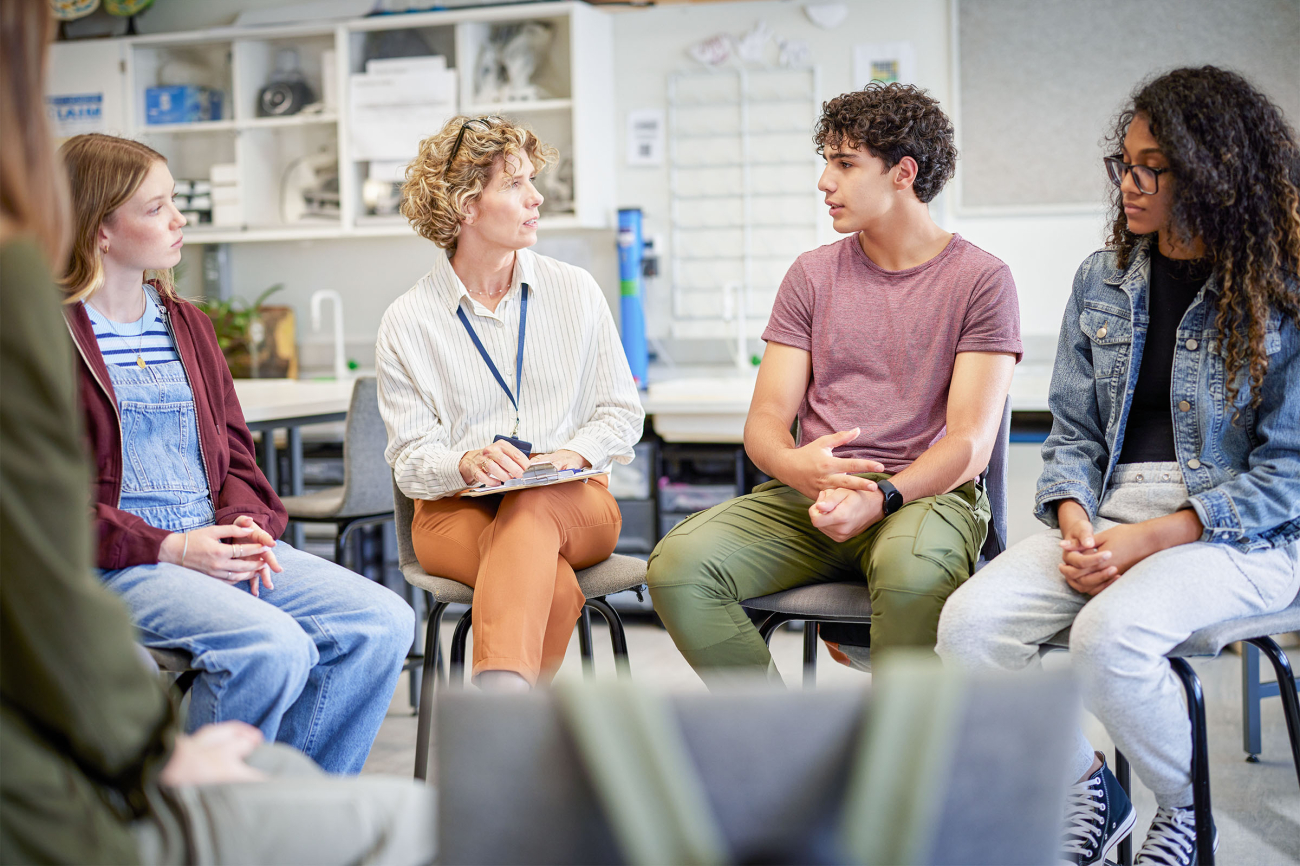 Lehrerin im Gespräch mit Schülerinnen und Schüler