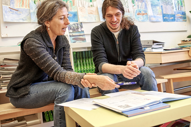 Eine Besprechung zwischen einer Lehrerin und einem Besuch im Klassenzimmer.