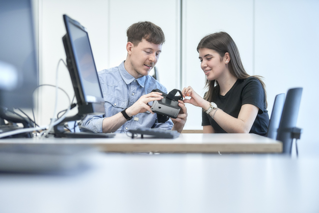 Studierende schauen sich gemeinsam eine VR-Brille an