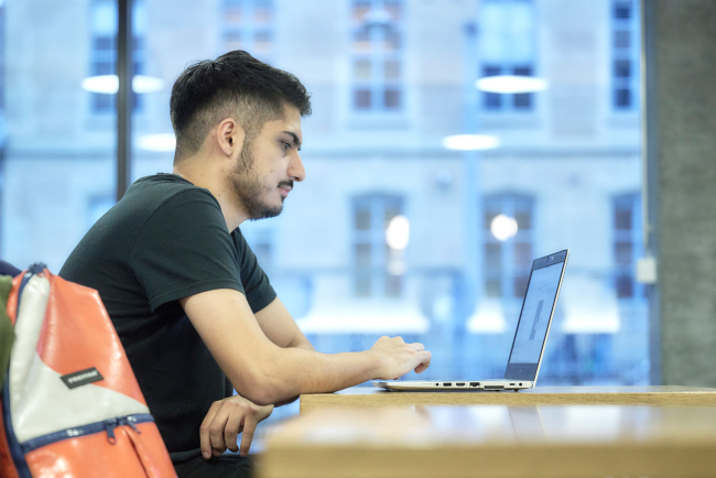 Mann sitzt an Tisch vor Laptop