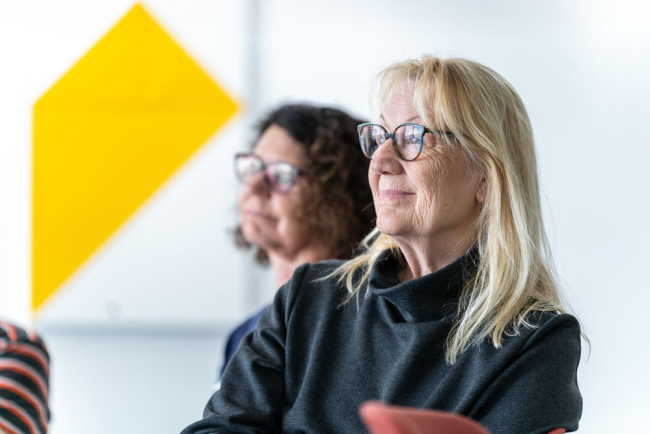 Zwei Frauen um die 60 hören zu in einem Kurs