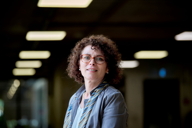Nathalie Culmone. Sie hat lockiges Haar und eine Rote Brille 